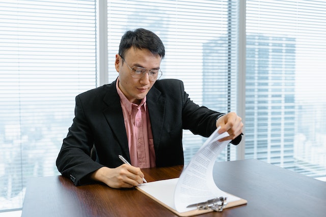 person looking over a contract on a clipboard
